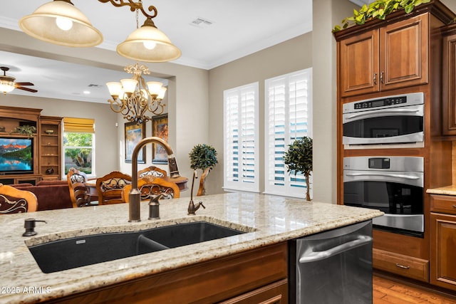 kitchen featuring visible vents, light wood-type flooring, ornamental molding, a sink, and light stone countertops