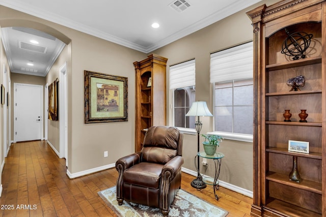 living area featuring hardwood / wood-style flooring, visible vents, arched walkways, and baseboards