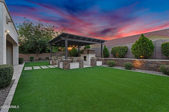 view of yard with an outdoor kitchen, a patio, a fenced backyard, and an outdoor stone fireplace