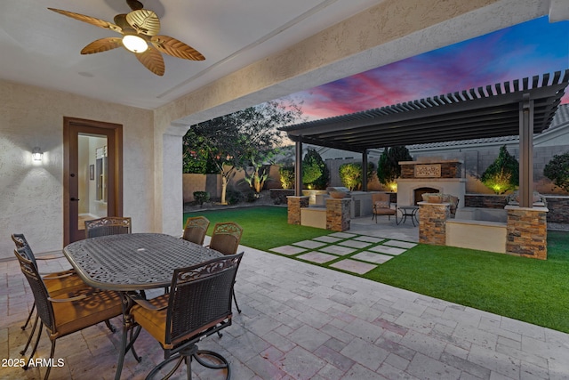 patio terrace at dusk with a lawn, outdoor dining area, a fenced backyard, an outdoor fireplace, and area for grilling