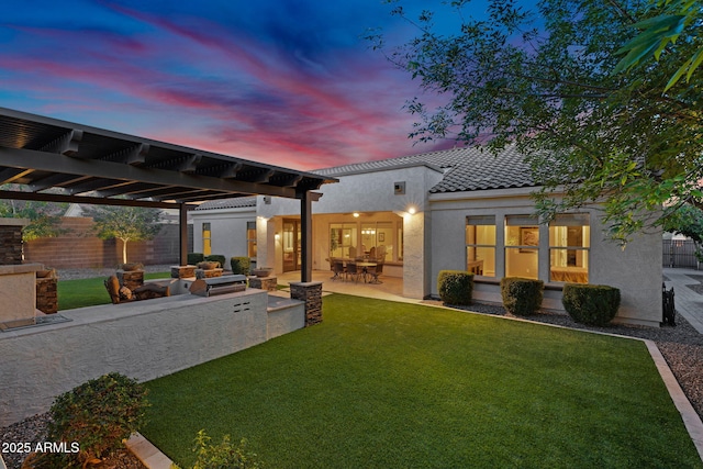 rear view of house with stucco siding, a patio, a lawn, and fence