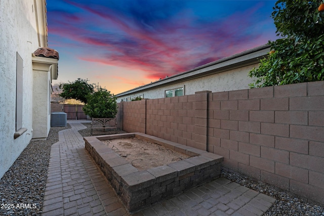 patio terrace at dusk featuring a fenced backyard