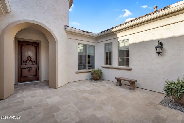 property entrance with stucco siding and a patio