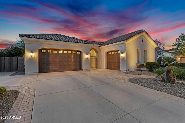 mediterranean / spanish-style home with stucco siding, driveway, a tile roof, and a garage