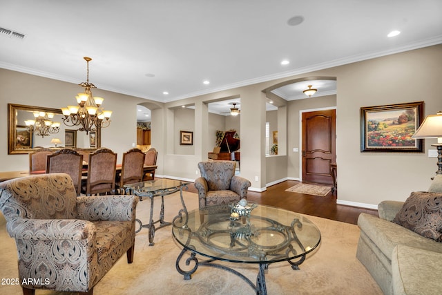 living area with visible vents, ornamental molding, wood finished floors, arched walkways, and baseboards