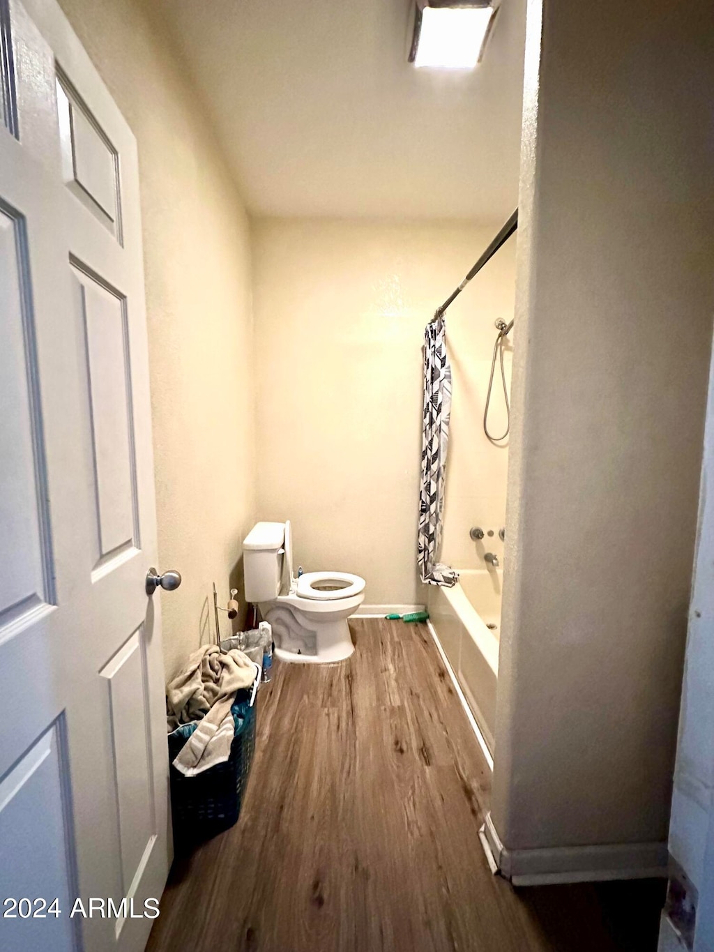 bathroom featuring shower / tub combo, hardwood / wood-style floors, and toilet