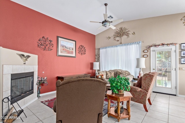 tiled living room featuring ceiling fan, lofted ceiling, and a tiled fireplace