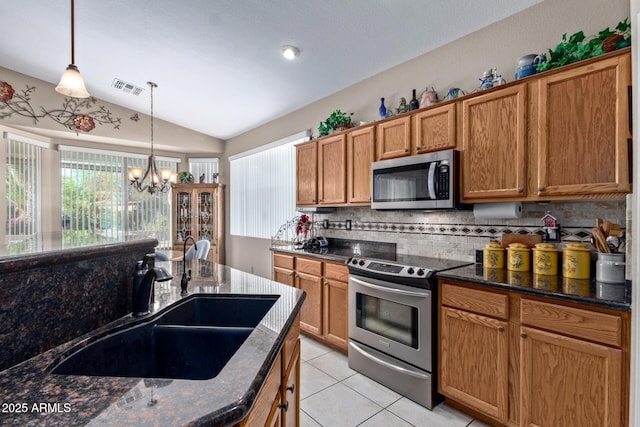 kitchen featuring an inviting chandelier, appliances with stainless steel finishes, lofted ceiling, pendant lighting, and sink