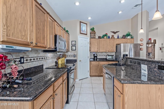 kitchen featuring light tile patterned floors, stainless steel appliances, dark stone counters, hanging light fixtures, and sink