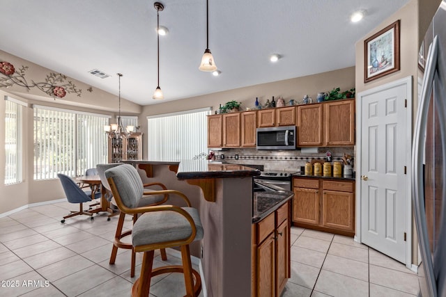 kitchen with vaulted ceiling, appliances with stainless steel finishes, pendant lighting, and a notable chandelier