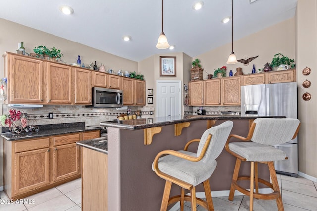 kitchen featuring a center island, stainless steel appliances, dark stone counters, hanging light fixtures, and light tile patterned flooring