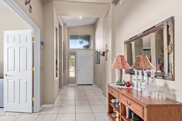 foyer featuring light tile patterned flooring and vaulted ceiling