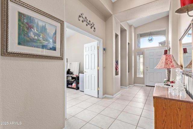 foyer entrance featuring light tile patterned floors and vaulted ceiling