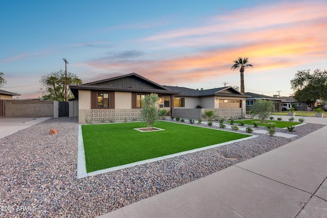 view of front of property featuring stucco siding, a yard, and fence