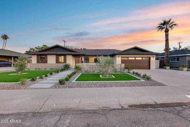 view of front facade with a garage, stucco siding, a front yard, and concrete driveway