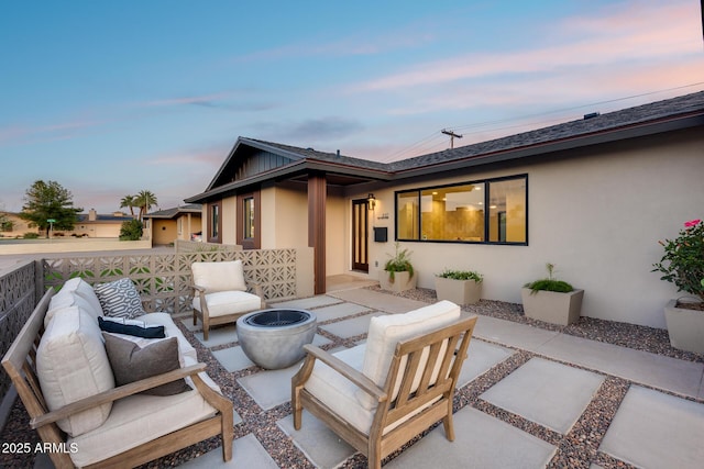back of property with an outdoor living space with a fire pit, a patio, and stucco siding