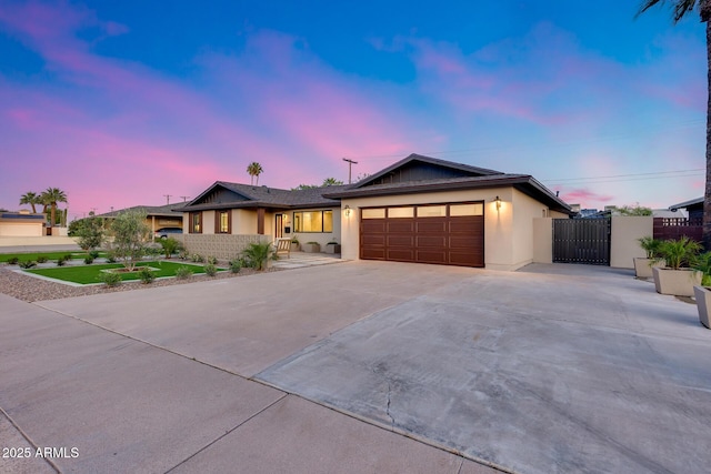 ranch-style home featuring driveway, a gate, a garage, fence, and stucco siding