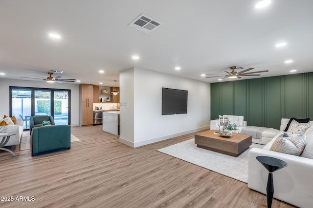 living area with visible vents, recessed lighting, ceiling fan, and a decorative wall