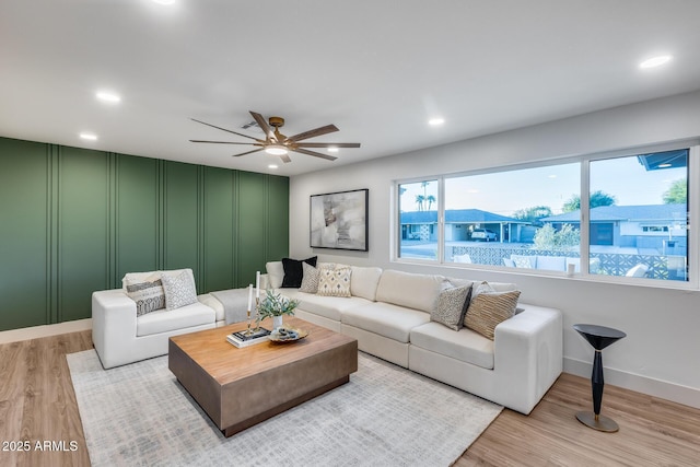 living room featuring a decorative wall, light wood-style floors, baseboards, recessed lighting, and a ceiling fan