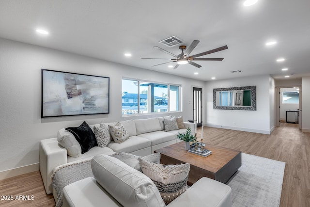 living room with a wealth of natural light, a ceiling fan, light wood-style flooring, and visible vents
