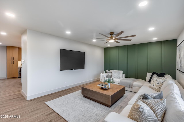 living room with light wood-style floors, ceiling fan, a decorative wall, and recessed lighting
