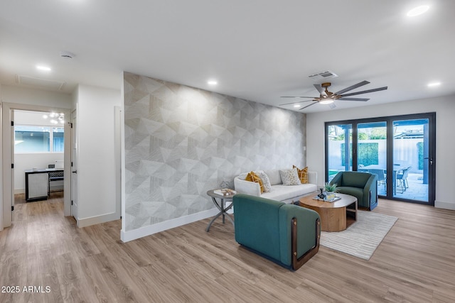 living room with baseboards, light wood finished floors, an accent wall, and visible vents