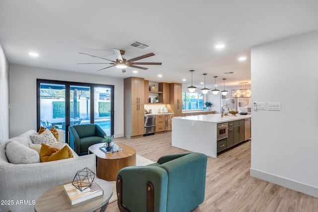 living room featuring baseboards, light wood-style flooring, and visible vents