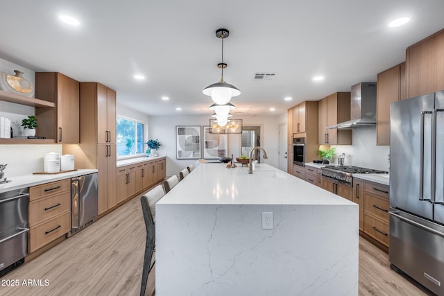 kitchen with visible vents, open shelves, wall chimney range hood, a sink, and appliances with stainless steel finishes