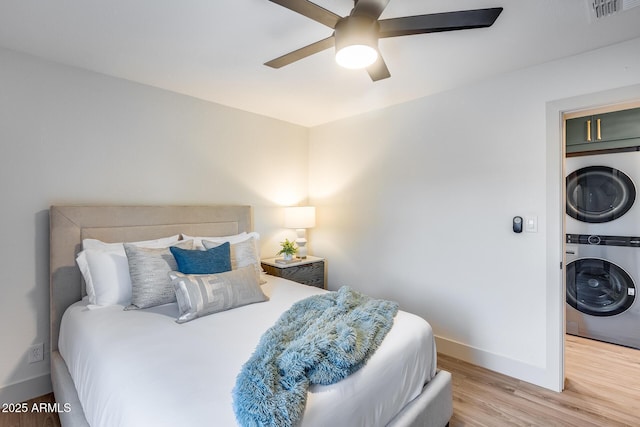 bedroom featuring baseboards, stacked washer and clothes dryer, light wood-type flooring, and visible vents