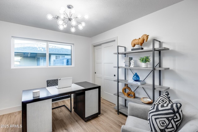 office space with a textured ceiling, a notable chandelier, and light wood finished floors