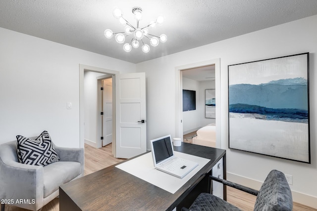 office space with a textured ceiling, baseboards, a chandelier, and light wood-style floors
