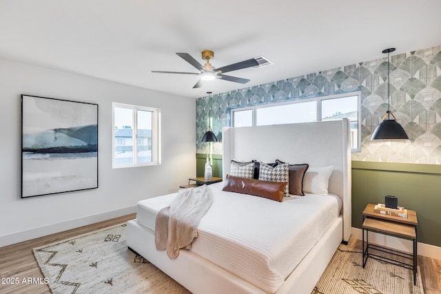 bedroom featuring visible vents, a ceiling fan, baseboards, and wood finished floors