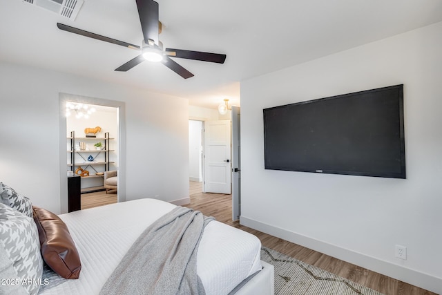 bedroom featuring baseboards, ceiling fan, wood finished floors, and visible vents