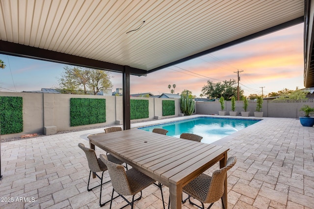 pool at dusk featuring a fenced in pool, a fenced backyard, a patio area, and outdoor dining area