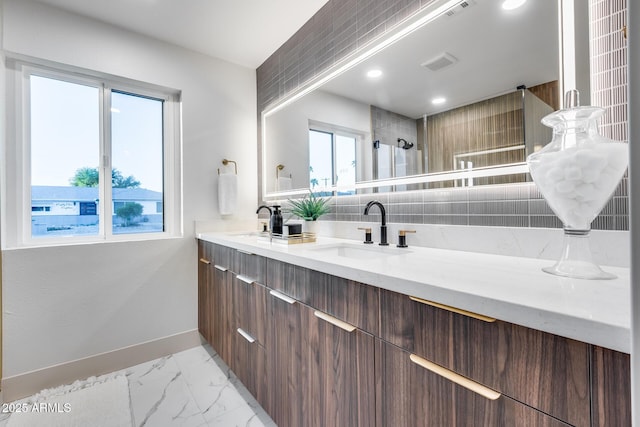 bathroom featuring visible vents, double vanity, marble finish floor, baseboards, and a sink