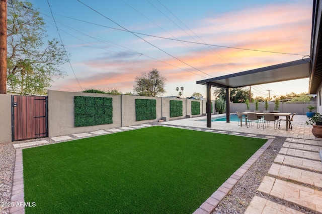 yard at dusk with a fenced backyard, a gate, a patio, and a fenced in pool
