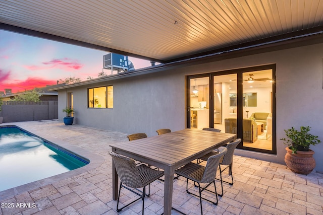 patio terrace at dusk featuring fence, a fenced in pool, central AC, and outdoor dining space