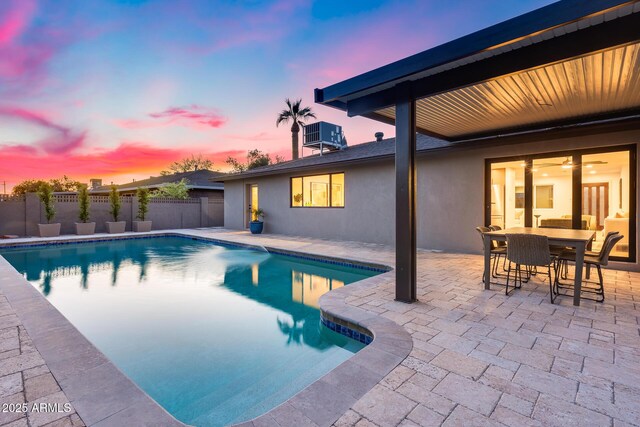 pool at dusk with a patio, fence, central air condition unit, and a fenced in pool