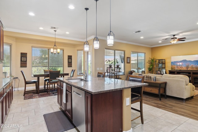 kitchen with light stone countertops, ceiling fan with notable chandelier, decorative light fixtures, a center island with sink, and stainless steel dishwasher