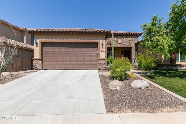 mediterranean / spanish house featuring stone siding, concrete driveway, an attached garage, and a tiled roof