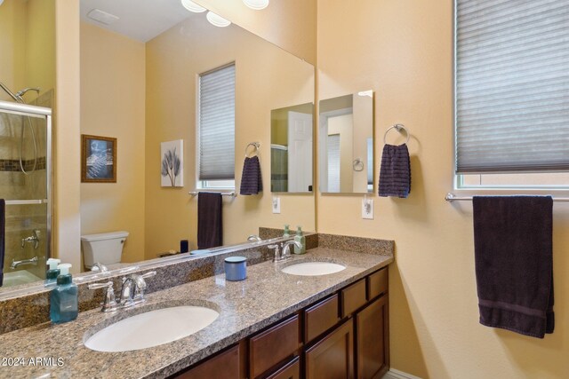 bathroom featuring vanity, toilet, and a shower with door