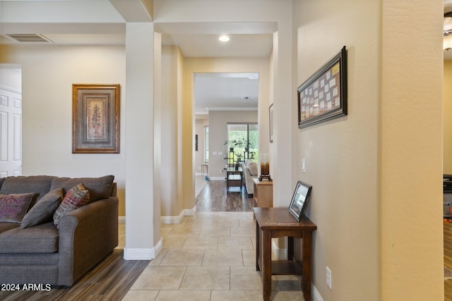 hallway featuring light tile patterned flooring, visible vents, and baseboards