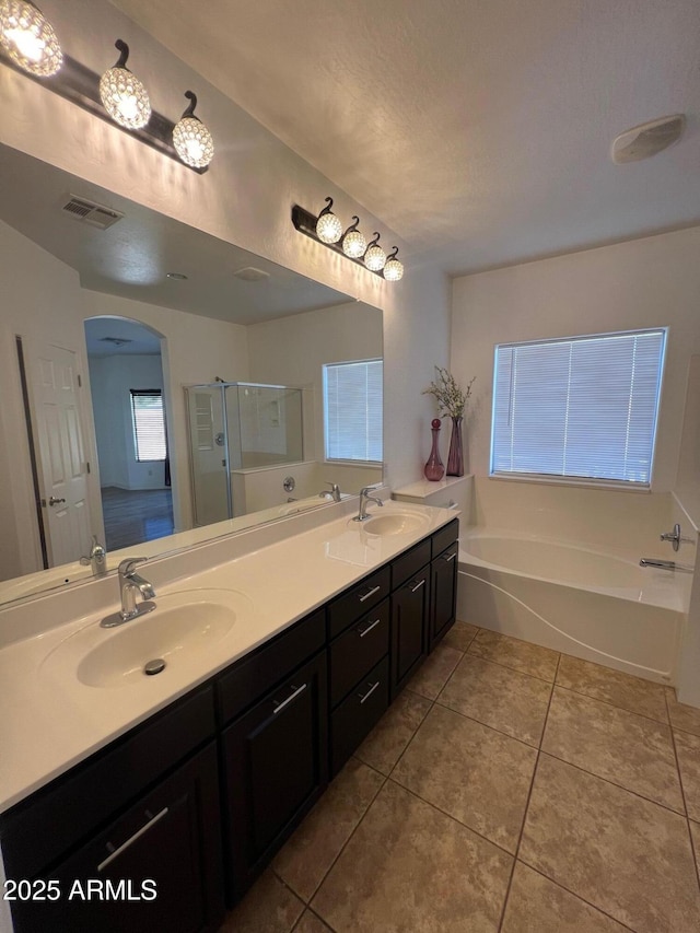 bathroom with tile patterned flooring, vanity, independent shower and bath, and a textured ceiling