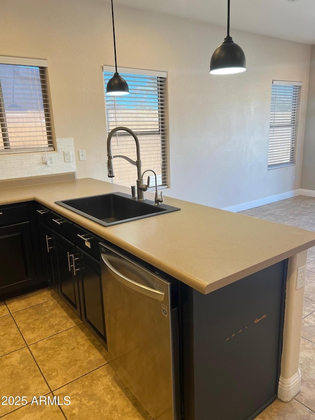 kitchen featuring pendant lighting, stainless steel dishwasher, sink, and decorative backsplash