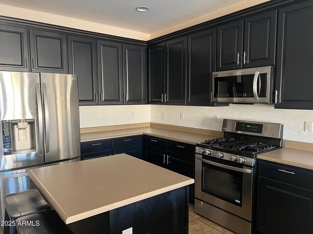 kitchen with a breakfast bar area, a center island, light tile patterned floors, stainless steel appliances, and backsplash