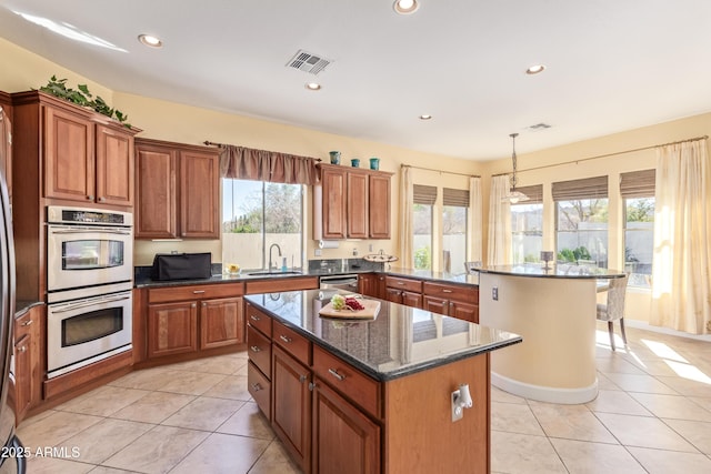 kitchen with brown cabinets, stainless steel appliances, a sink, and a center island