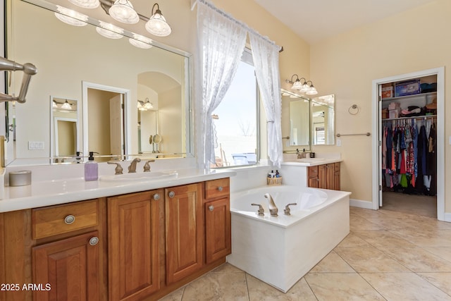 full bath featuring a spacious closet, vanity, a bath, and tile patterned floors