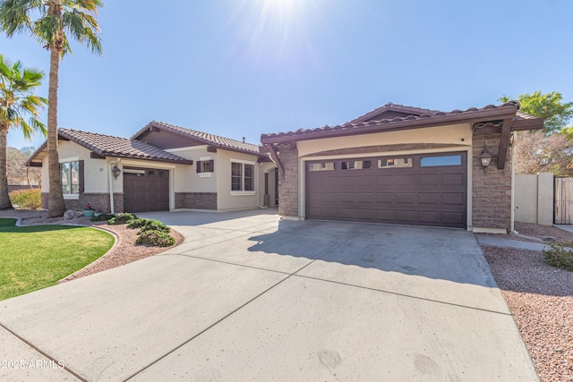 mediterranean / spanish house featuring a tiled roof, stone siding, an attached garage, and driveway