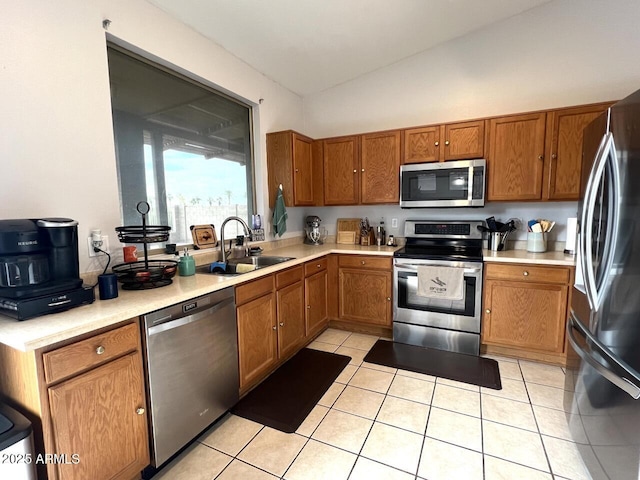 kitchen featuring light tile patterned floors, appliances with stainless steel finishes, brown cabinets, light countertops, and a sink