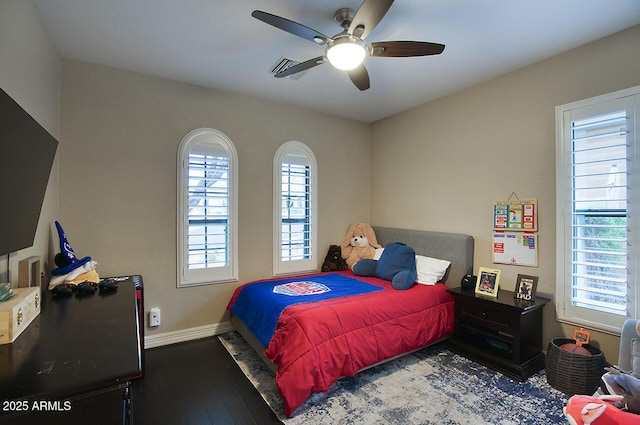 bedroom featuring a ceiling fan, baseboards, multiple windows, and hardwood / wood-style floors